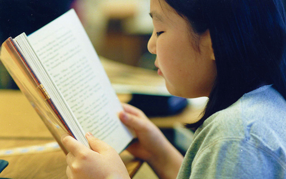 Foto di una bambina che legge un libro.